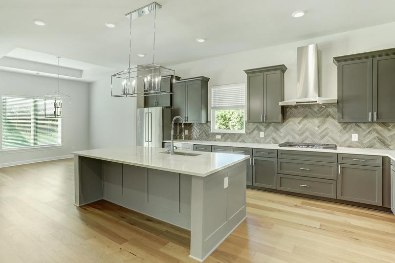 The kitchen has dark grey cabinetry, quartz countertops and stainless steel appliances.