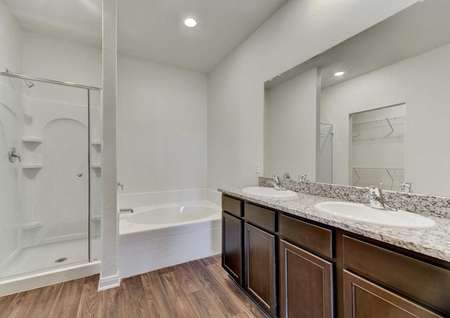 Travis bathroom with two drop-in sinks, granite countertop, and separate shower and bathtub