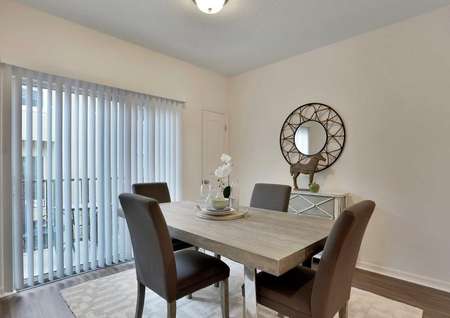 The Pine Key floor plans dining area has brown chairs, a light brown table and a rug under them.