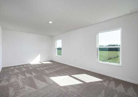 Sizable master bedroom with carpeted floors and two large windows. 