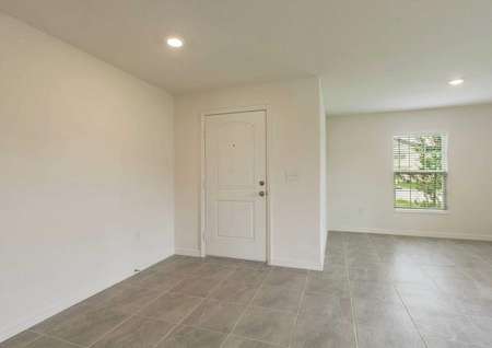 View of the front door from the Estero plan's living room that has tile flooring, white walls and recesses lighting.