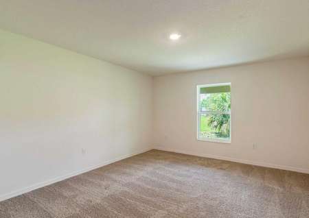 Spare room of the Anastasia floor plan with a large window, light brown carpet and a light fixture on the ceiling.