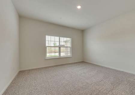 The master bedroom has brown carpet, white walls and a double-window with front yard views.