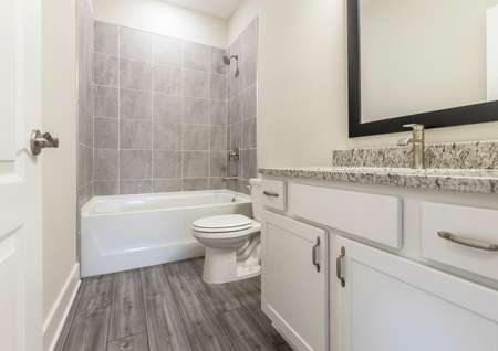 Secondary bathroom with spacious granite countertops and modern hardware. 