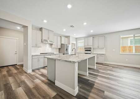 Stunning kitchen with a large granite island, tile backsplash, and wood flooring. 
