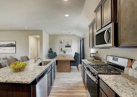 Staged kitchen with brown cabinetry and granite countertops.
