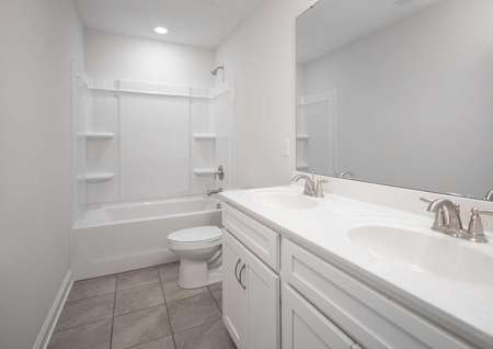 Fripp guest bathroom with two sinks, shower/tub unit, and modern white fixtures