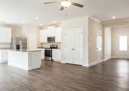 Kitchen off the entryway with vinyl flooring, granite countertops and white cabinetry. 