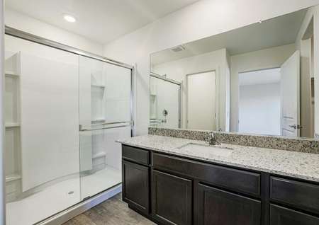 Attached to the bedroom, the master bathroom features a walk-in shower and wood-style flooring.