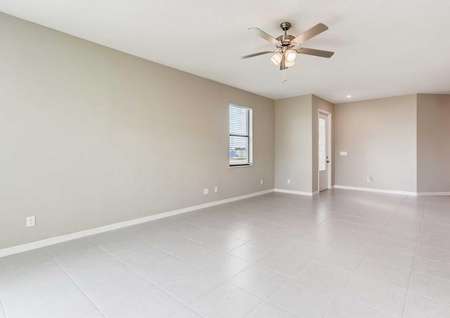 The spacious living room in the Santa Maria model home. Tile flooring, a ceiling fan, white baseboards and tan walls