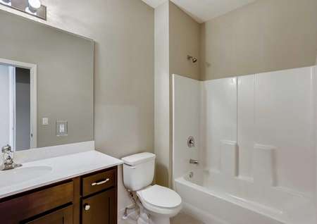 The secondary bathroom in the Patricio model home. White shower and tub, quartz countertops, designer hardware and tile flooring