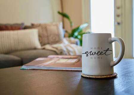 Home sweet home coffee mug on coffee table with couch in the background. 