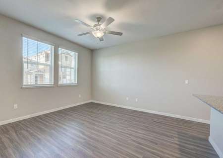 The Empire floor plan living room has two windows, a ceiling fan with a light and vinyl wood flooring.