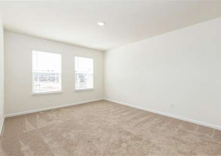 Spacious master bedroom with two windows, carpet, recessed light.