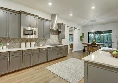 Staged kitchen with gray cabinetry and white countertops.