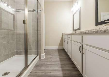 Full bathroom with a large standing shower and double sinks with granite countertops.