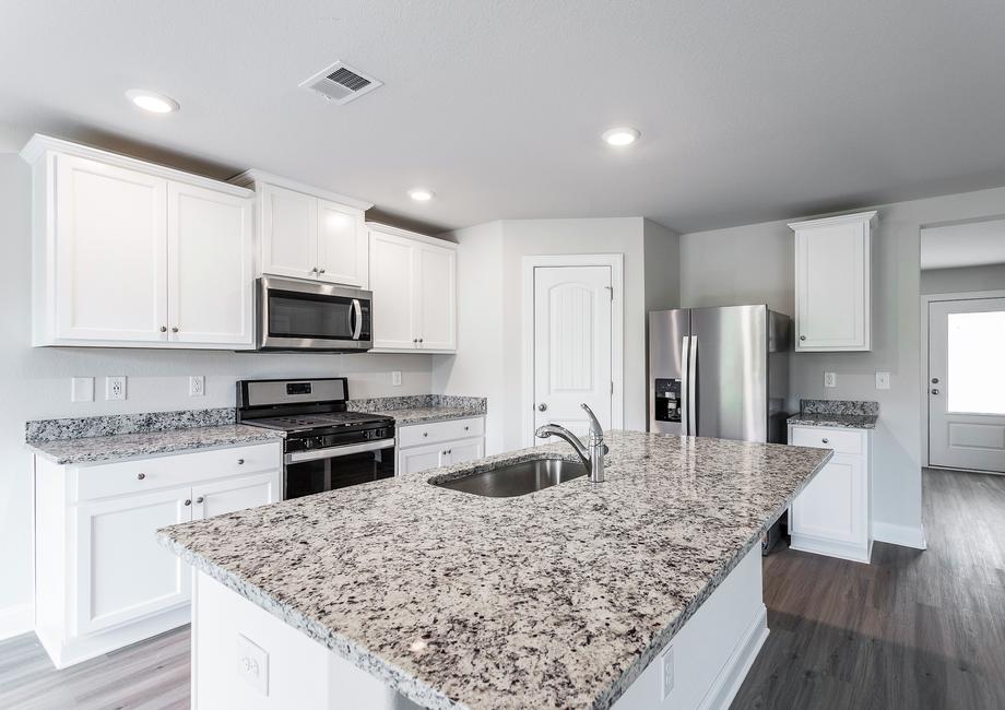 Kitchen with granite countertops and white cabinets with hardware.