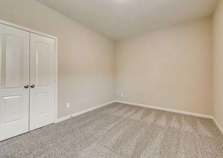 Secondary bedroom with tan walls, white trim and brown carpet.