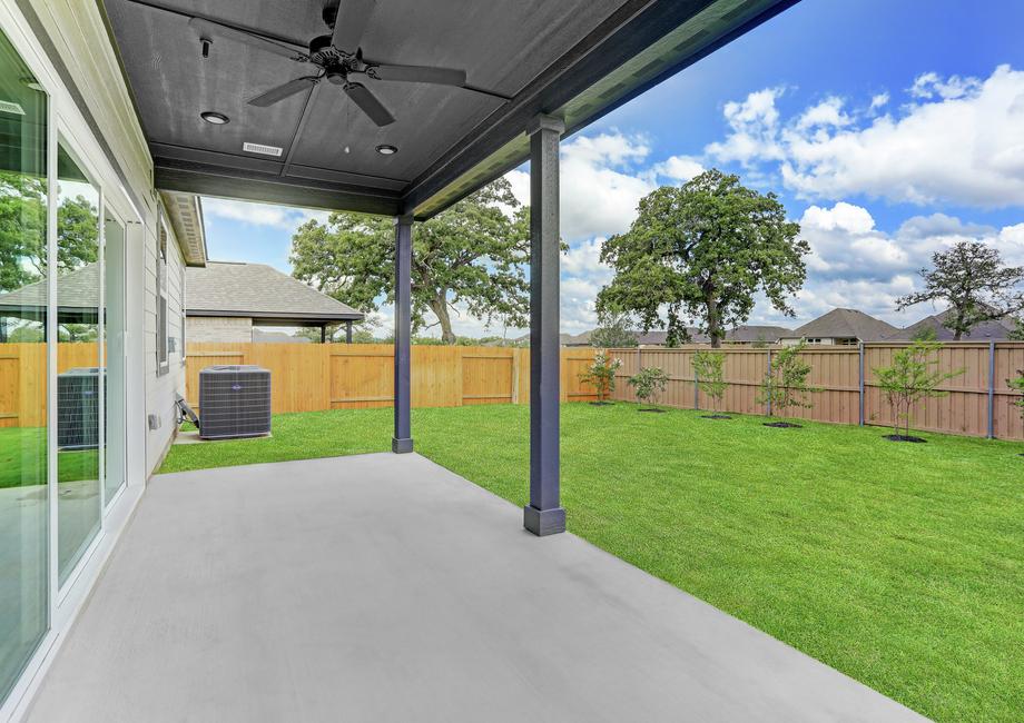 Covered back patio with a ceiling fan and large sliding glass doors.