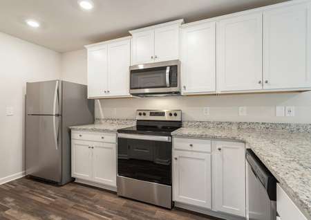 Kitchen with granite countertops, white cabinetry and stainless steel appliances.