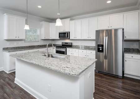 Kiawah plan's kitchen with granite countertops, white cabinets, stainless steel appliances & an island that has a sink.