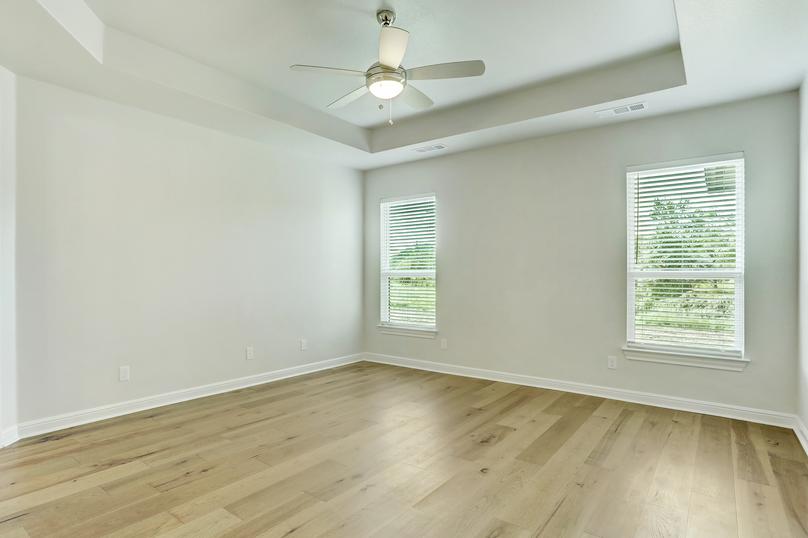 The master suite of the Mantle plan has gorgeous wood floors and a ceiling fan.