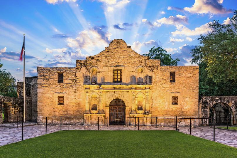 San Antonio, Texas The Alamo famous outpost with a deep history showing remaining stone structure, wooden arched doorway, and green grassy grounds in the front