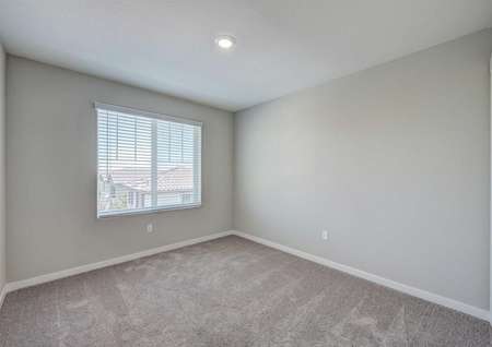 A spare bedroom upstairs in the Loomis floor plan with carpet floors, a large window and a ceiling light fixture.
