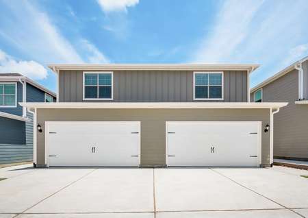 Two townhomes, each with their own two-car garage and long driveway.