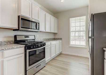 White kitchen cabinets, stainless gas range, built-in microwave, stainless refrigerator window with blinds