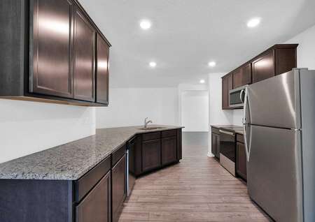 Long, granite countertops in a kitchen that also features brand-new stainless steel appliances. 