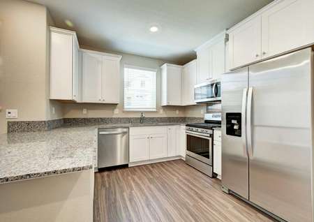 The kitchen with white wooden cabinets, granite countertops and all stainless steel appliances in the Kennedy floor plan.