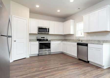 Chef-ready kitchen with white cabinets, granite countertops, and stainless appliances.