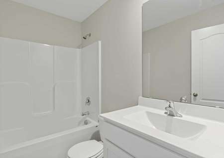 Burton white on white bathroom with modern fixtures, tub/shower combo, and large vanity mirror