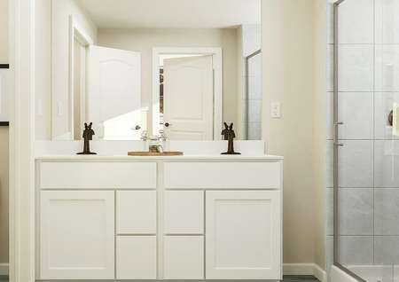 Rendering of master bathroom showing a
  white toilet and abstract art on left, large white cabinet vanity with double
  sinks center, and glass shower door on right.