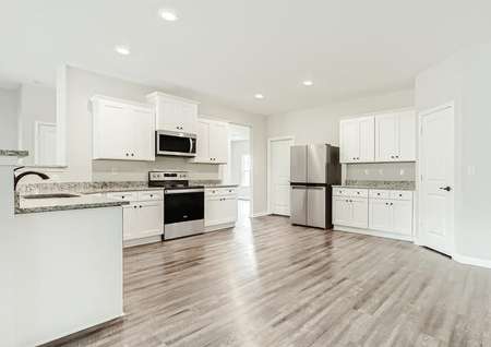 Upgraded kitchen with crown molding on the white cabinets and wood-style flooring throughout. 