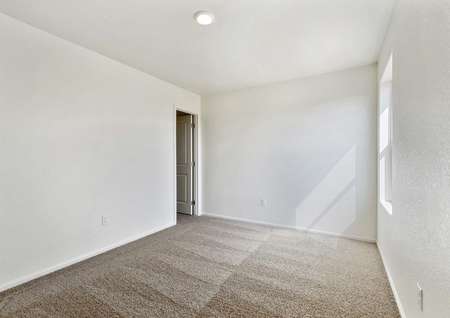 Guest bedroom with a window, tan carpet, and plenty of space for your belongings.