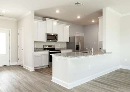 Kitchen with white cabinets, gray granite countertops, stainless appliances, recessed lighting and plank flooring.