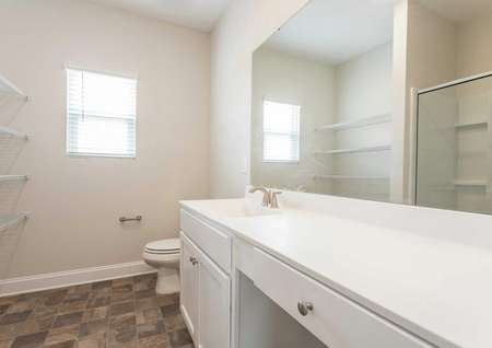 Alexander master bathroom with brown tile floors, large white vanity, and storage space