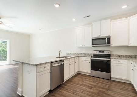 Large kitchen with granite countertops, stainless steel appliances and vinyl flooring.