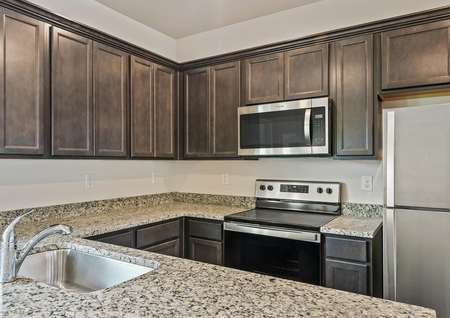The kitchen has sprawling granite countertops and brown cabinetry.