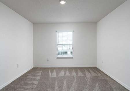 Carpeted spare bedroom with recessed lighting and a window that lets in natural light.