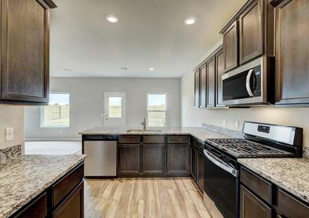 The chef-ready kitchen has sprawling granite countertops and brown cabinetry.