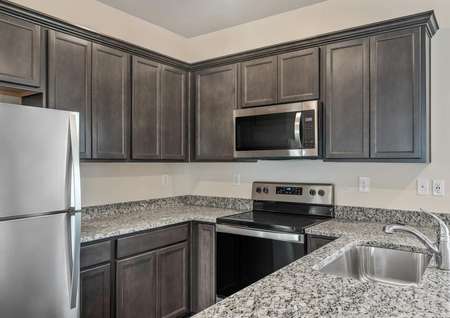 The kitchen has brown cabinetry and a full suite of stainless steel appliances.