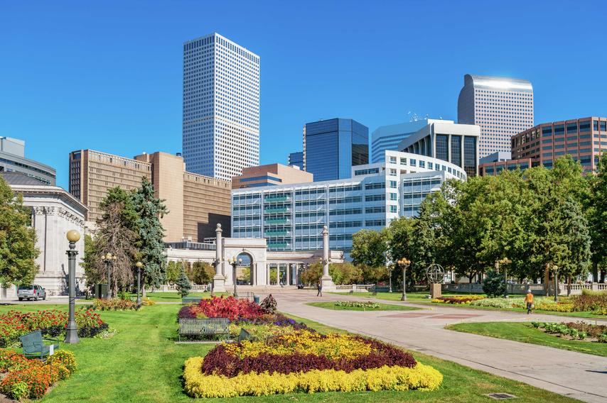 Denver, Colorado Civic Center Park downtown with lush gardens that have blooming yellow, red, and maroon color flowers, walking paths, and green trees
