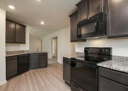 Pecos kitchen with recessed lights, black appliances, and brown custom cabinets