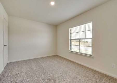 Sabine bedroom finished with lightly colored carpet, large street facing window with blinds, and recessed light