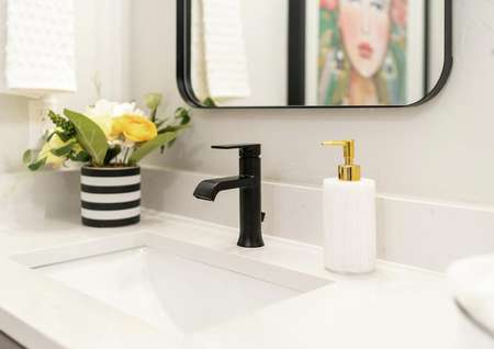 Staged second bathroom with a black faucet and white granite countertops. 