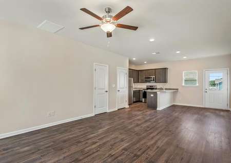 This home has an open layout with dark wood-like flooring and tan walls with white trim.