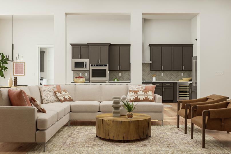 Rendering of the open floor plan living
  room featuring a sectional couch, coffee table and two leather armchairs. The
  kitchen and dining room are visible in the background.